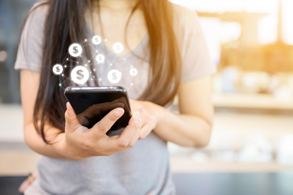 Mujer con celular desde donde salen signos pesos